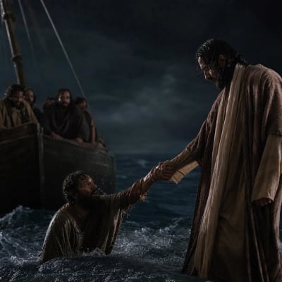 Jesus catching Peter by the hand on rough water beside the disciples' boat during a windy night.